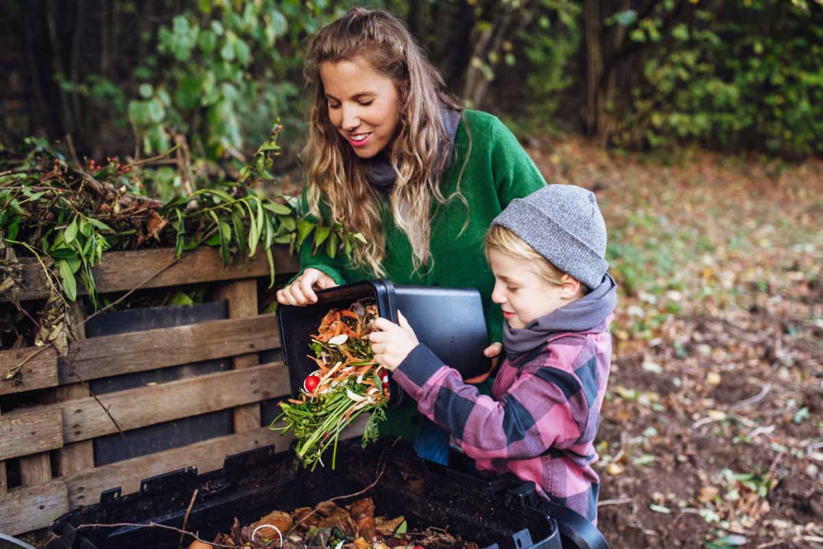 Une femme et son enfant qui font du compost dans le fond du jardin.