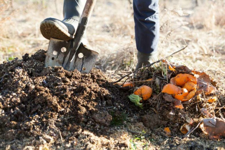 Une personne qui retourne son tas de compost.