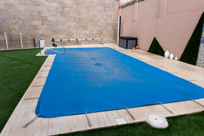 Une bâche de piscine pour limiter l'évaporation et les pertes de chaleur, celle-ci est équipée de tendeurs pour la maintenir en place.