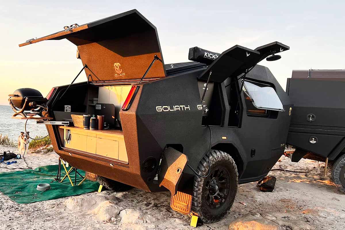 Une caravane dotée d'une cuisine extérieure avec barbecue et d'une douche.