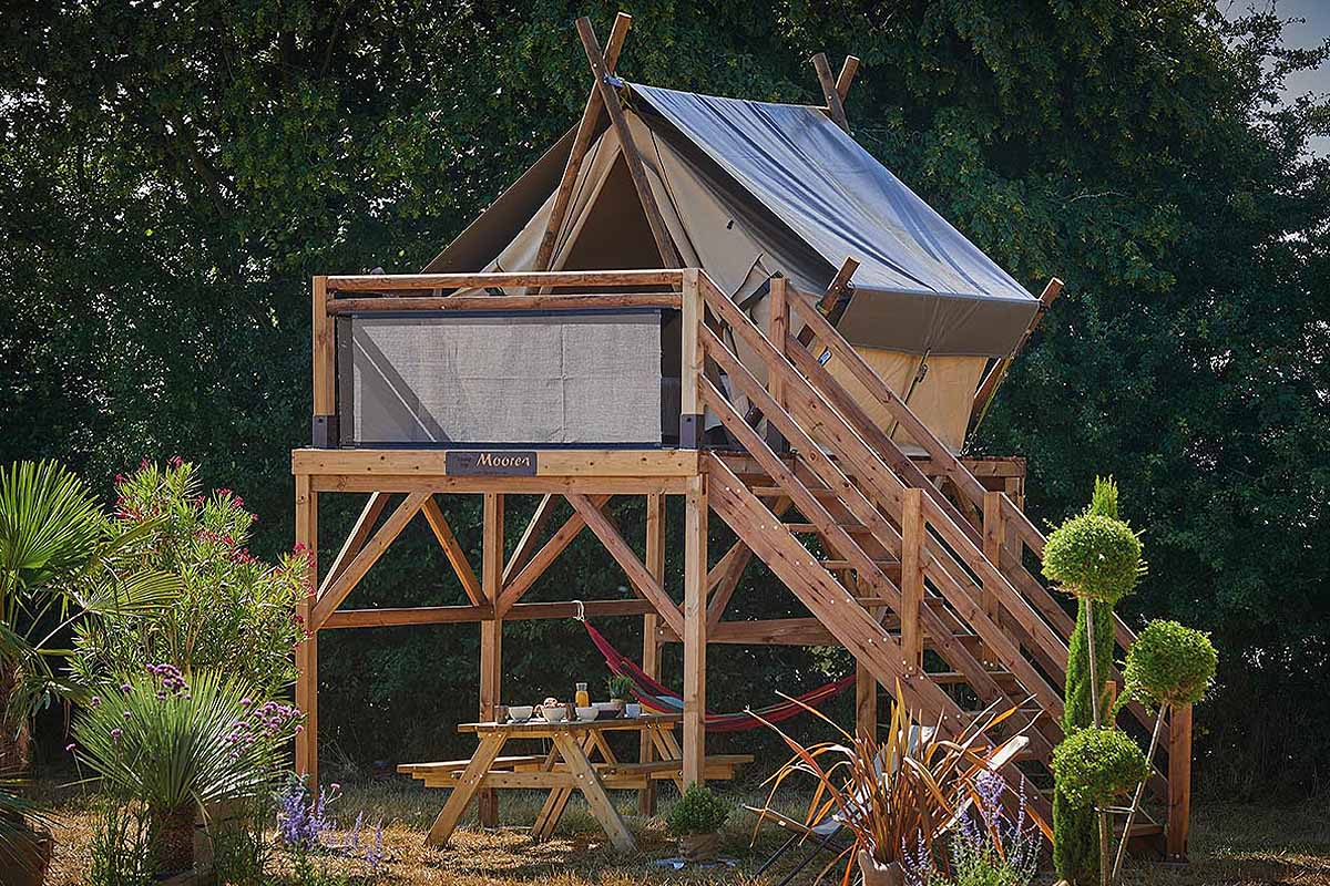 Une tente de camping montée sur une terrasse en bois.