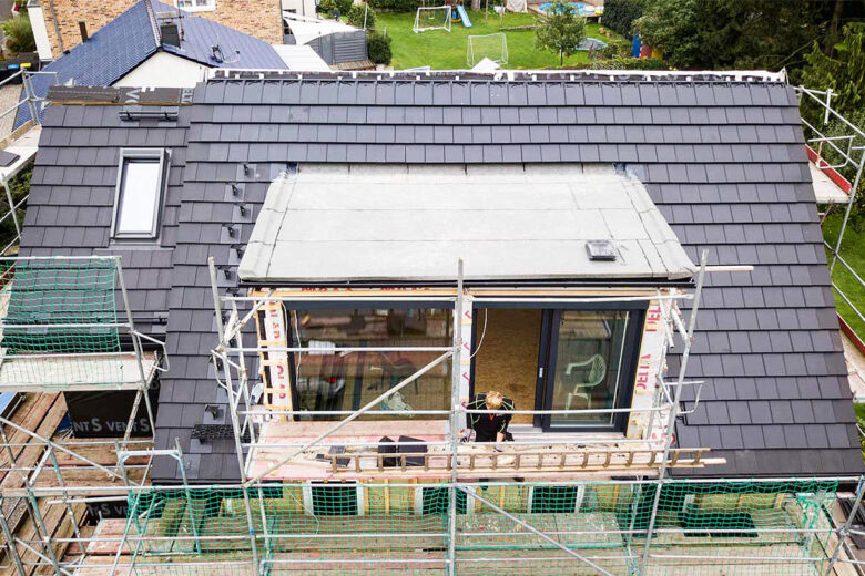 Un chantier de rénovation de toiture avec des tuiles solaires.