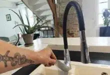 Un homme qui ouvre un robinet pour faire couler de l'eau.