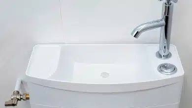 Un lavabo au-dessus du réservoir des toilettes.