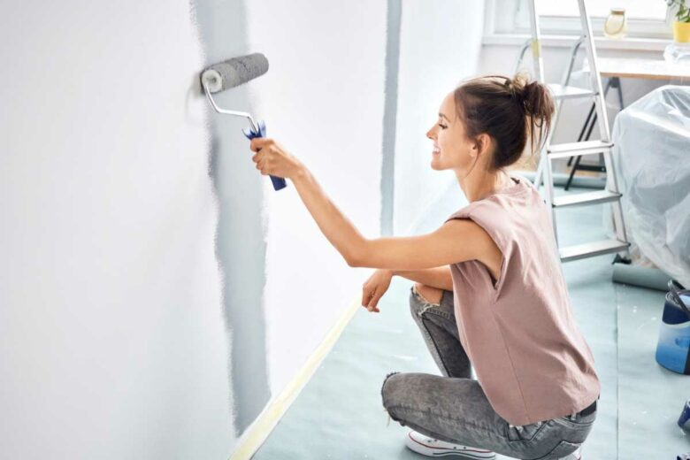 Une femme qui repeint un mur au rouleau.