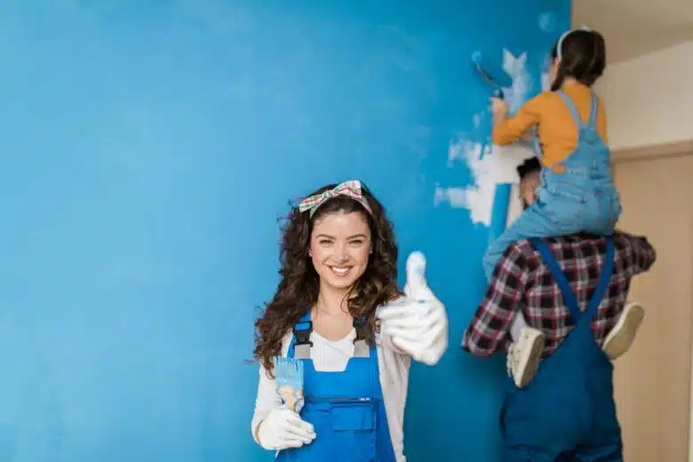 Une femme heureuse de repeindre un mur en famille.