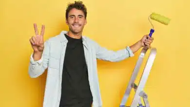 Un homme heureux du résultat de sa peinture jaune.