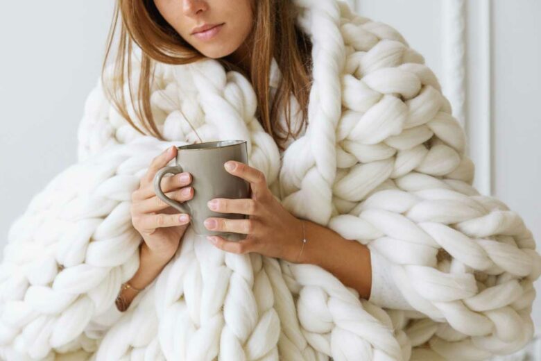 Une femme bien au chaud sous un plaid en laine Mérinos pour se protéger du froid.