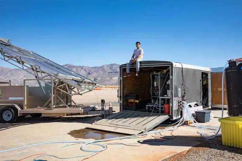 Un membre de l'équipe de développement assis sur une remorque abritant le système de dessalement par électrodialyse, le système est connecté à de véritables nappes phréatiques, à des réservoirs d'eau et à des panneaux solaires.