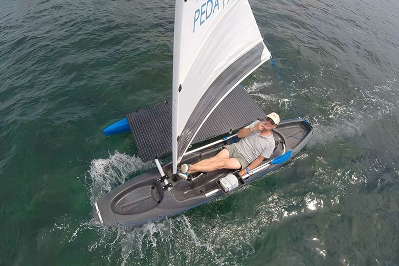 Un homme vogue sur l'eau avec un Pedayak solaire à voile.