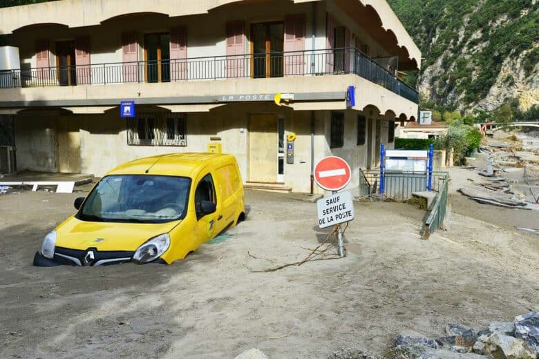 Une voiture de la poste et la route ensevelies par la boue.