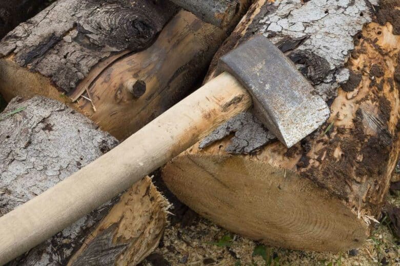 Une hache sur des rondins de bois.