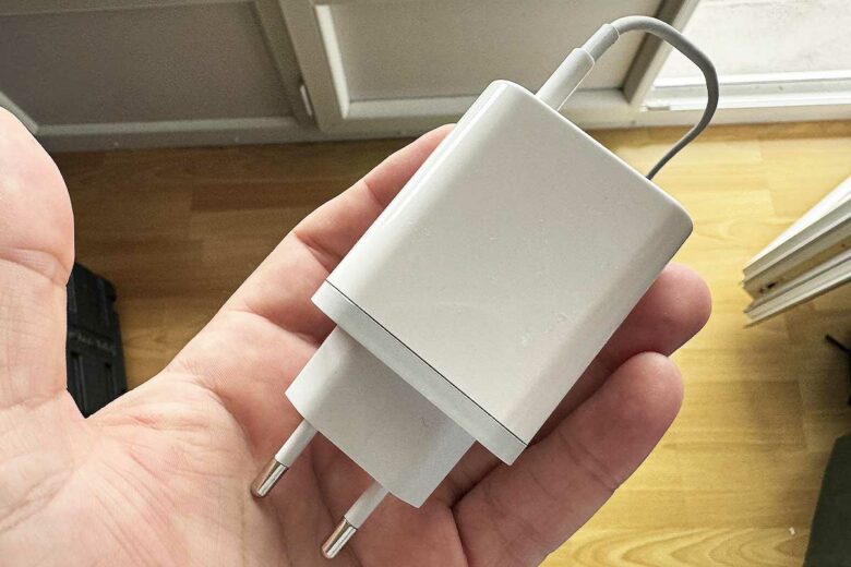 Un chargeur de téléphone tenu en main.