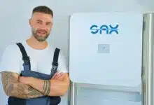 Un technicien à côté d'une batterie résidentielle Sax Power.