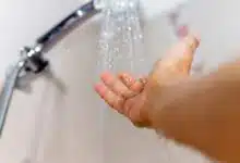 Une main vérifie la température de l'au de la douche.