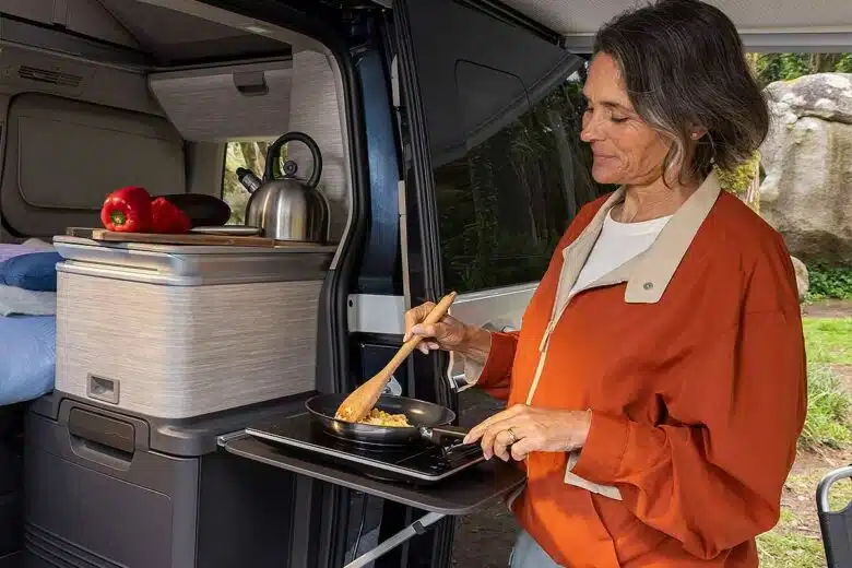 Une femme cuisinant à l'extérieur de son van.