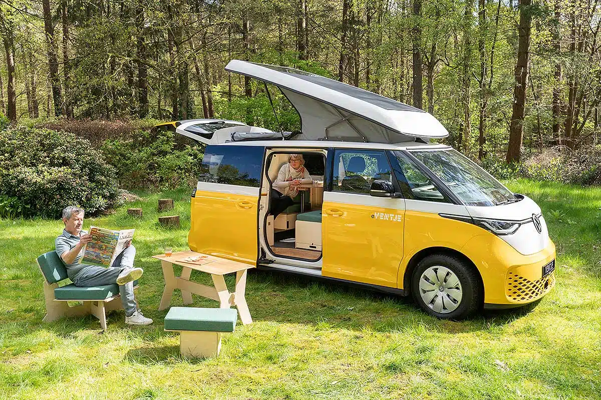 Un couple se détend dans la nature à côté de leur van aménagé.