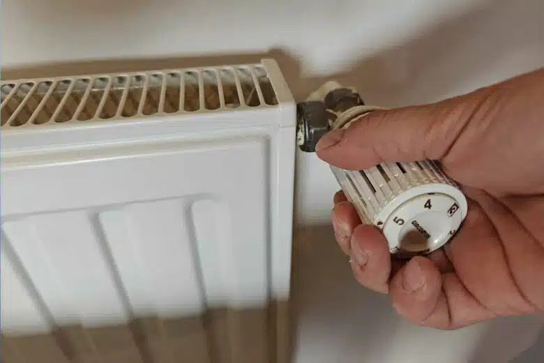 Une personne règle le thermostat d'un radiateur.