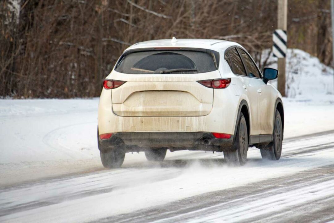 Une voiture qui roule sur une route enneigée.