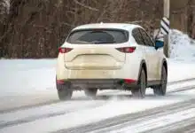 Une voiture qui roule sur une route enneigée.