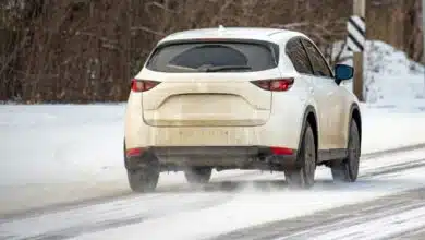 Une voiture qui roule sur une route enneigée.