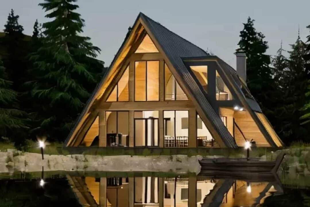 Une maison en A et son reflet face à un plan d'eau.