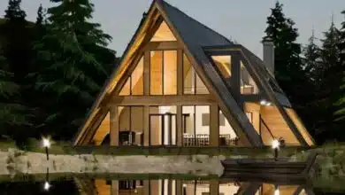 Une maison en A et son reflet face à un plan d'eau.