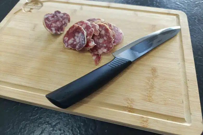 Une planche à découper en bois avec du saucisson.