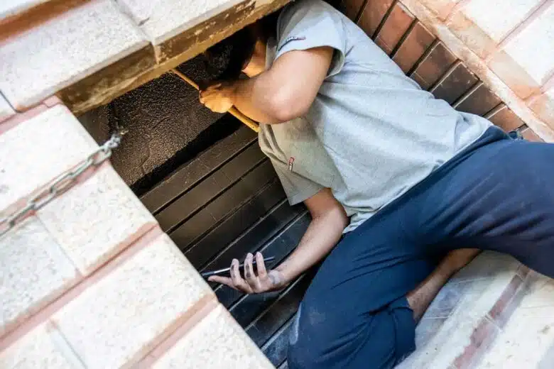 Un homme ramone sa cheminée de l'intérieur.