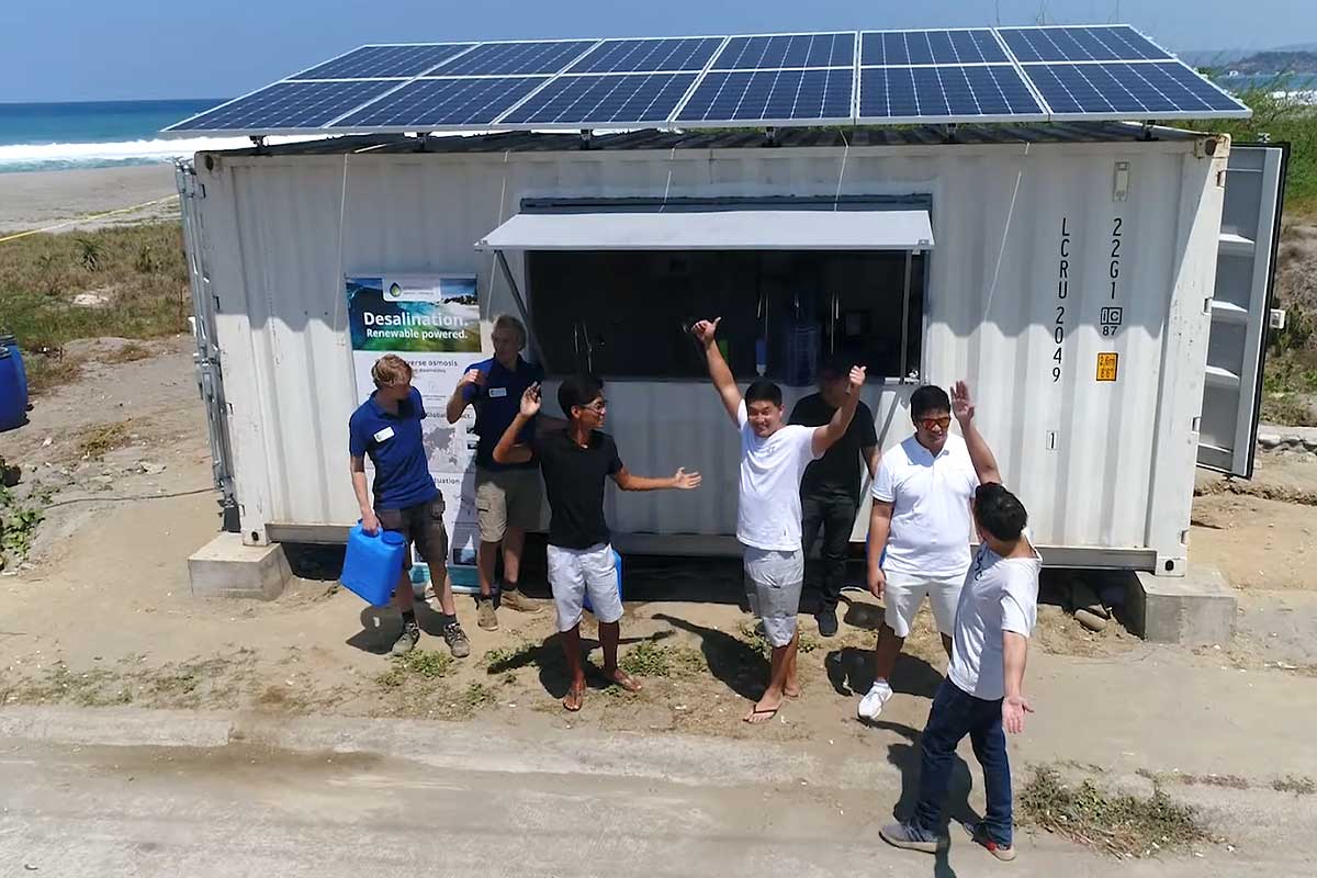 Des personnes devant une structure de dessalement qui fournit de l'eau potable.