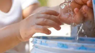 Un enfant les mains sous l'eau.