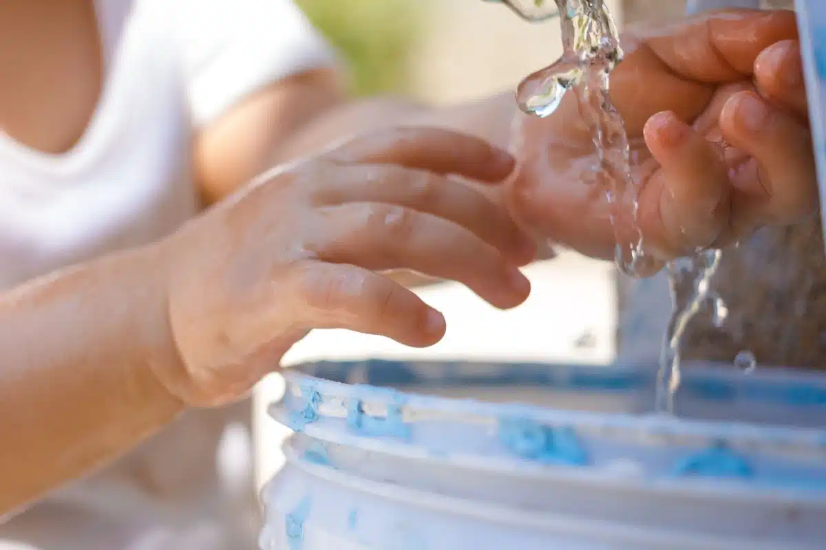 Un enfant les mains sous l'eau.