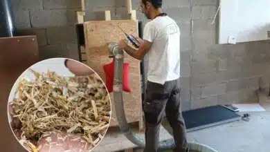 Un homme insuffle de la paille hachée dans un caisson d'isolation.