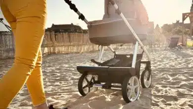 Une femme pousse une poussette dans le sable.