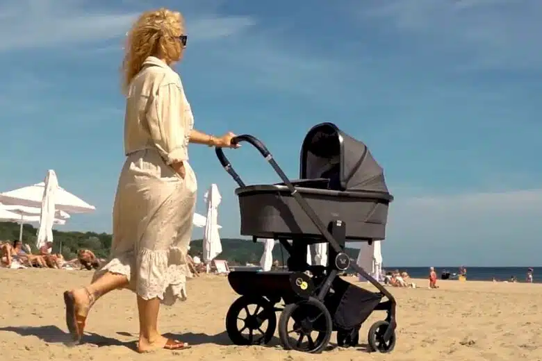 Une femme poussant son enfant dans un landeau.