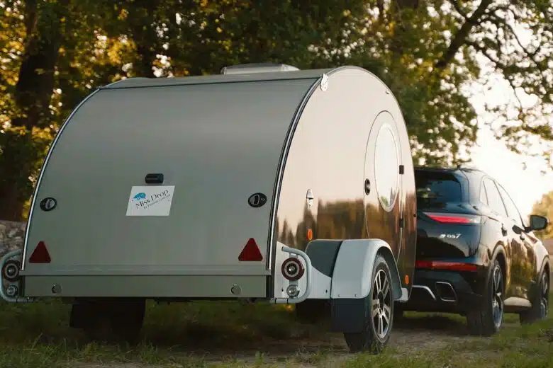 Une caravane teardrop tractée par une voiture.