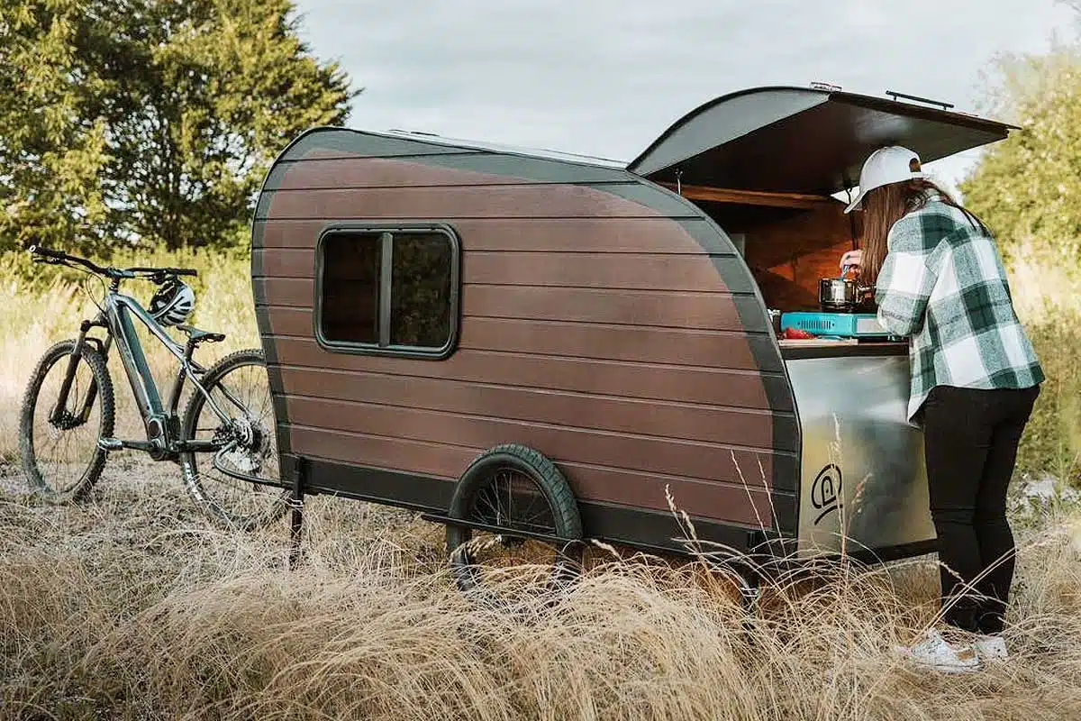 Une mini-caravane tractée par un vélo.