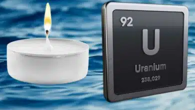 Une bougie et le symbole chimie de l'uranium sur fond d'océan.