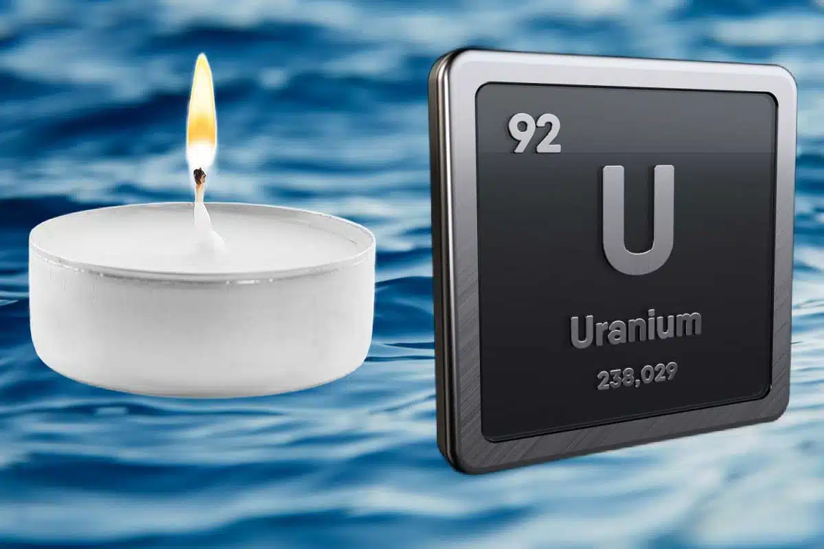 Une bougie et le symbole chimie de l'uranium sur fond d'océan.