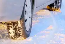 Une voiture circule sur une route enneigée.