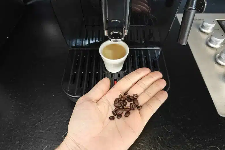 Un homme tient des grains de café devant sa machine.