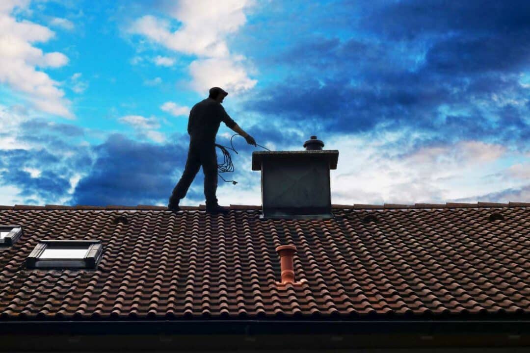 Un homme sur le toit d'une maison pour le ramonage.