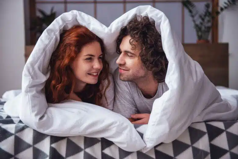 Un couple se regarde sous une couette.