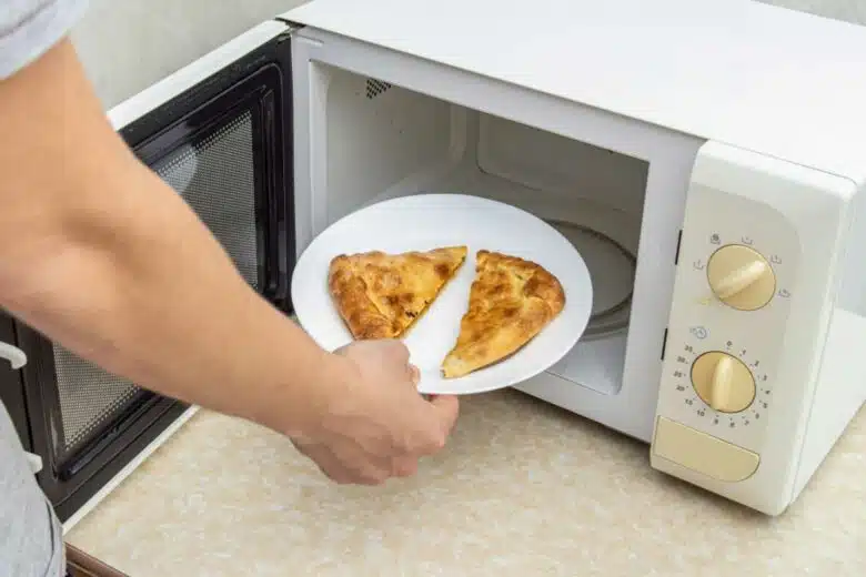 Un homme met des parts de pizza au micro-onde.