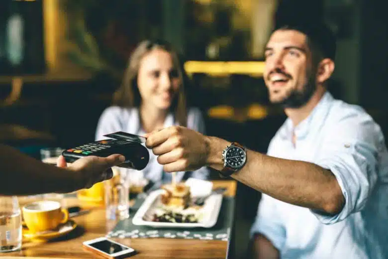 Un homme paie son addition à table avec un TPE.