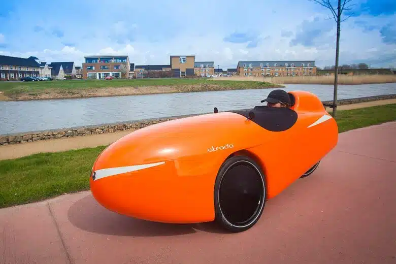 Un velomobile circule sur les bords d'un fleuve.