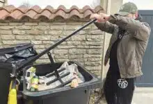 Un homme compacte ses poubelles pour réduire leur volume.