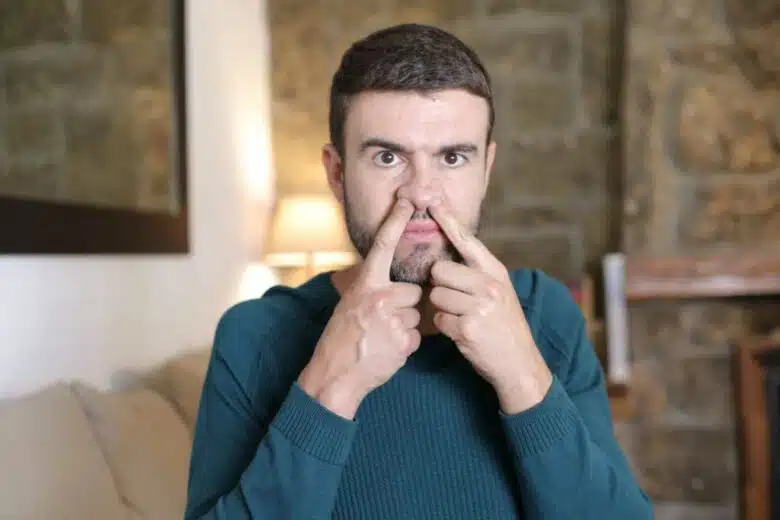 Un homme avec les deux doigts dans le nez.