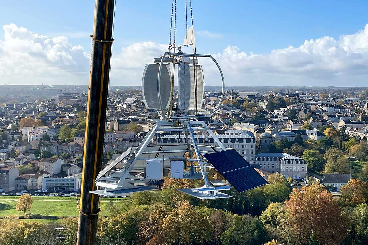 Une éolienne déplacée par une grue pour son installation sur un toit d'immeuble.