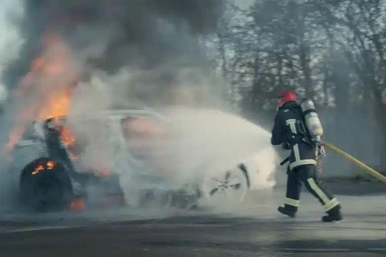 Un pompier éteint un incendie de voiture.